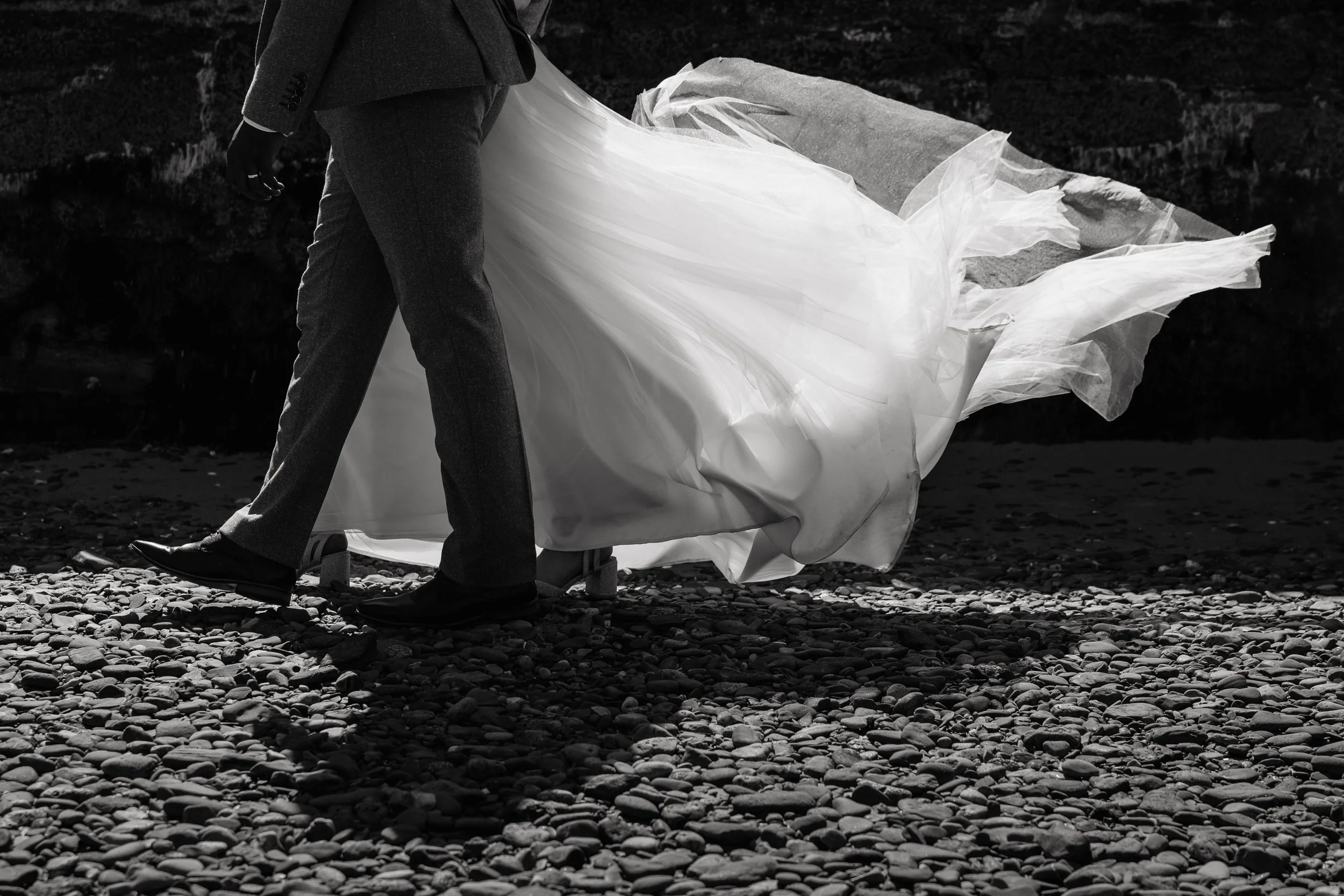 black and white image of a bride's dress blowing in the wind