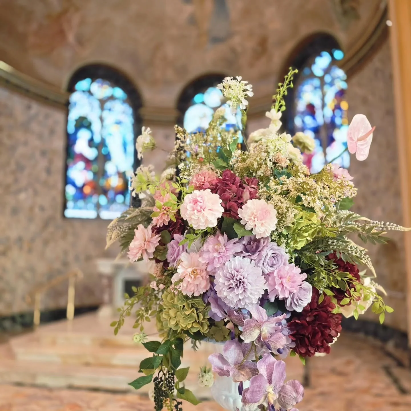 Blush pinks, soft lilacs, rich burgundy tones, and layered greenery, creating an elegant, garden-inspired arrangement with plenty of depth and texture.

Our Lady of Mt. Carmel Catholic Church