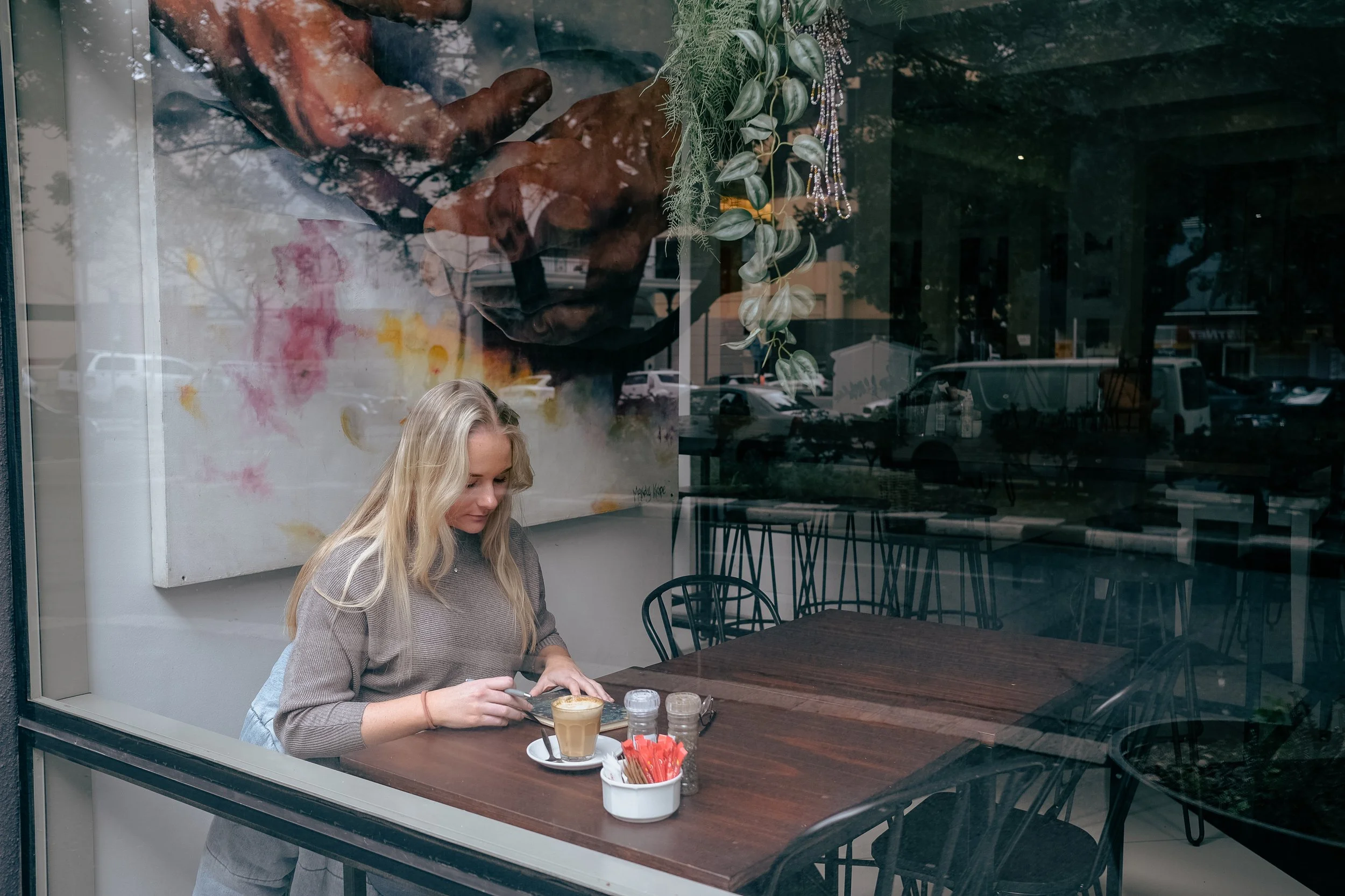 girl sitting at a cafe window with a coffee