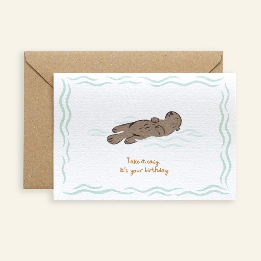 Otter Birthday Card with kraft envelope on plain background
