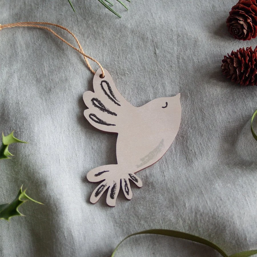 Dove wooden Christmas decoration on linen background with holly, pine cones and ribbon