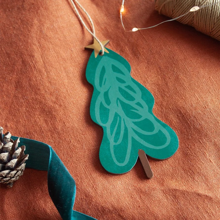 Tree wooden Christmas decoration styled on orange linen background with ribbons and lights