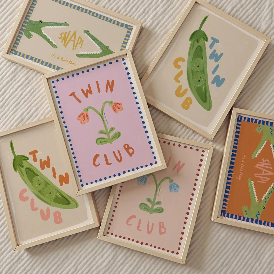 Twin Club twin nursery print collection layed on rug in wooden frames