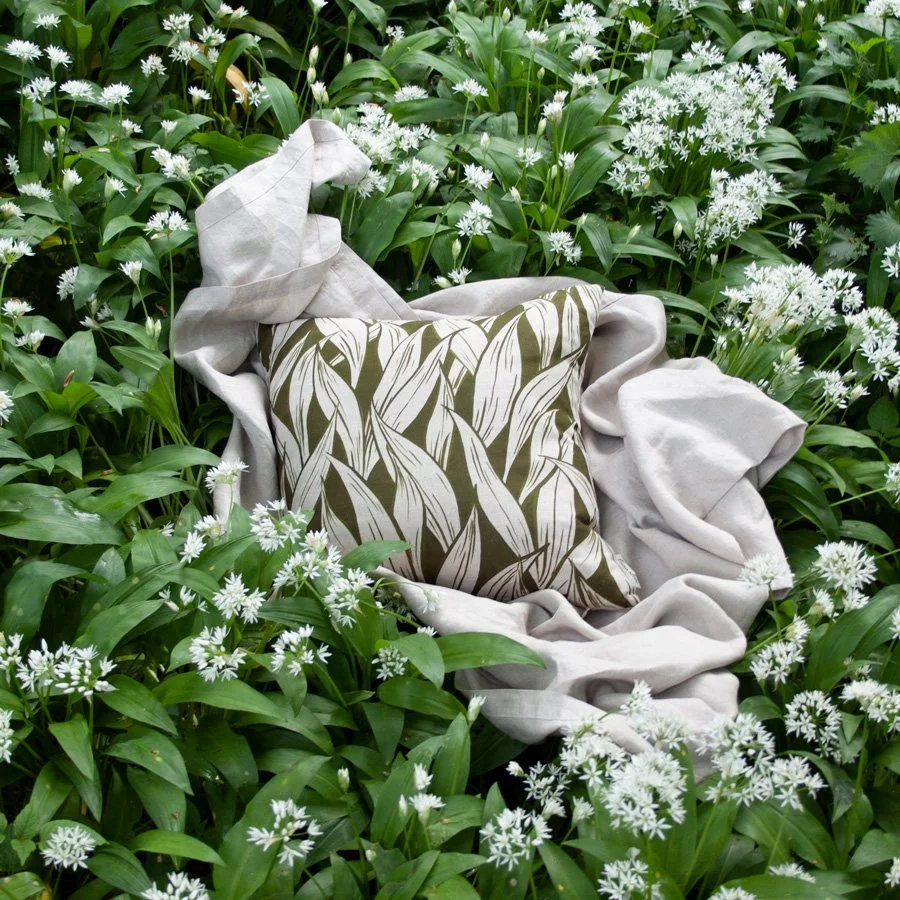 Wild Garlic Olive Green Fabric as a cushion styled amongst wild garlic flowers