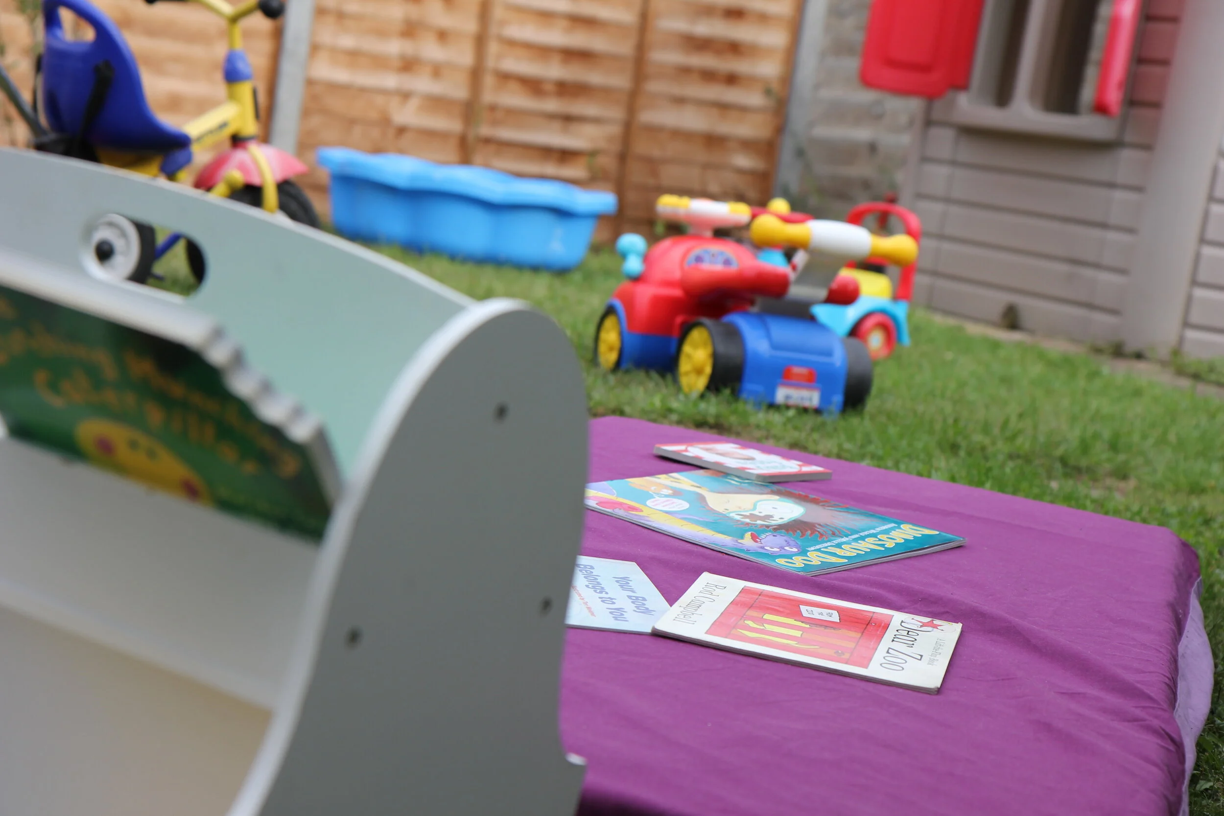 Large outdoor play area with playhouse, mud-kitchen, slides, sensory toys in a home-from-home childcare environment.