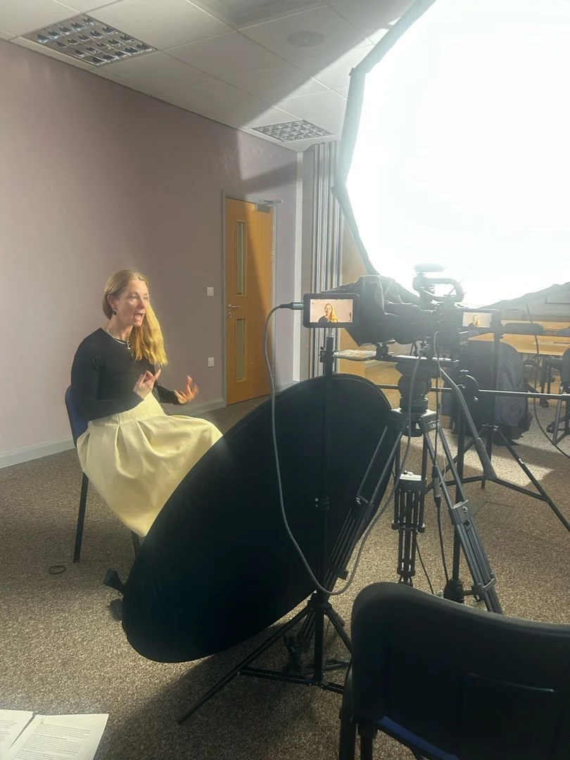 Photo of Susie in front of a podcasting studio to record the videos