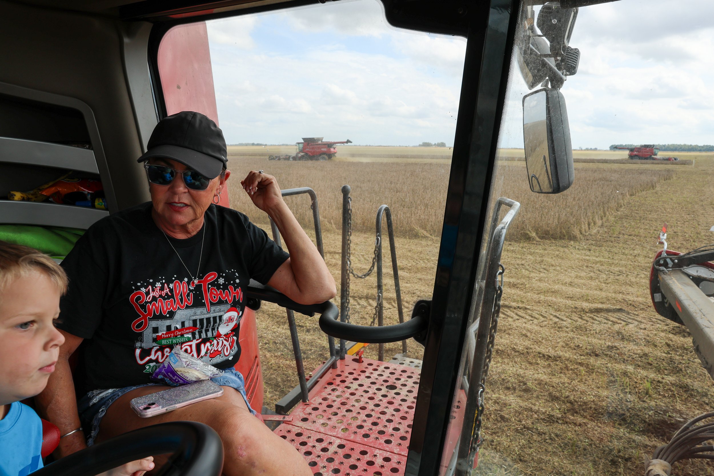 Tina sits alongside Baker at the front of a combine during soybean harvest at Brown Brothers Farm. The pair accompanied one of her South African farmhands around the property. Behind Tina, expansive bean fields make up a sliver of the thousands of ac
