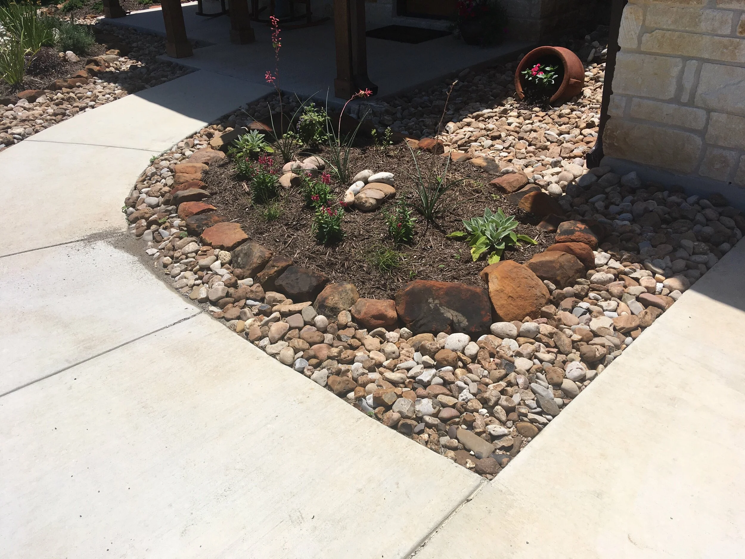 Raised bed with moss rock edging and river rock covered beds