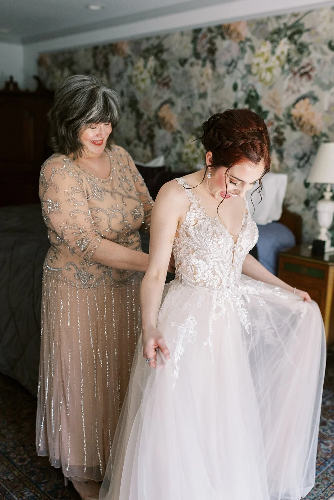Bride admiring her wedding dress as her mother helps her get ready at the Houdini Estate