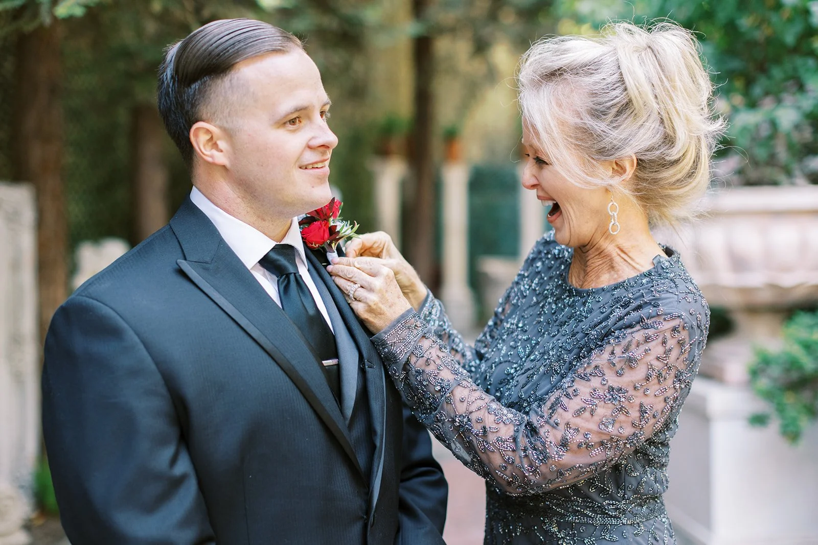 Excited mother pinning a boutonniere on her son’s lapel before his Los Angeles elopement