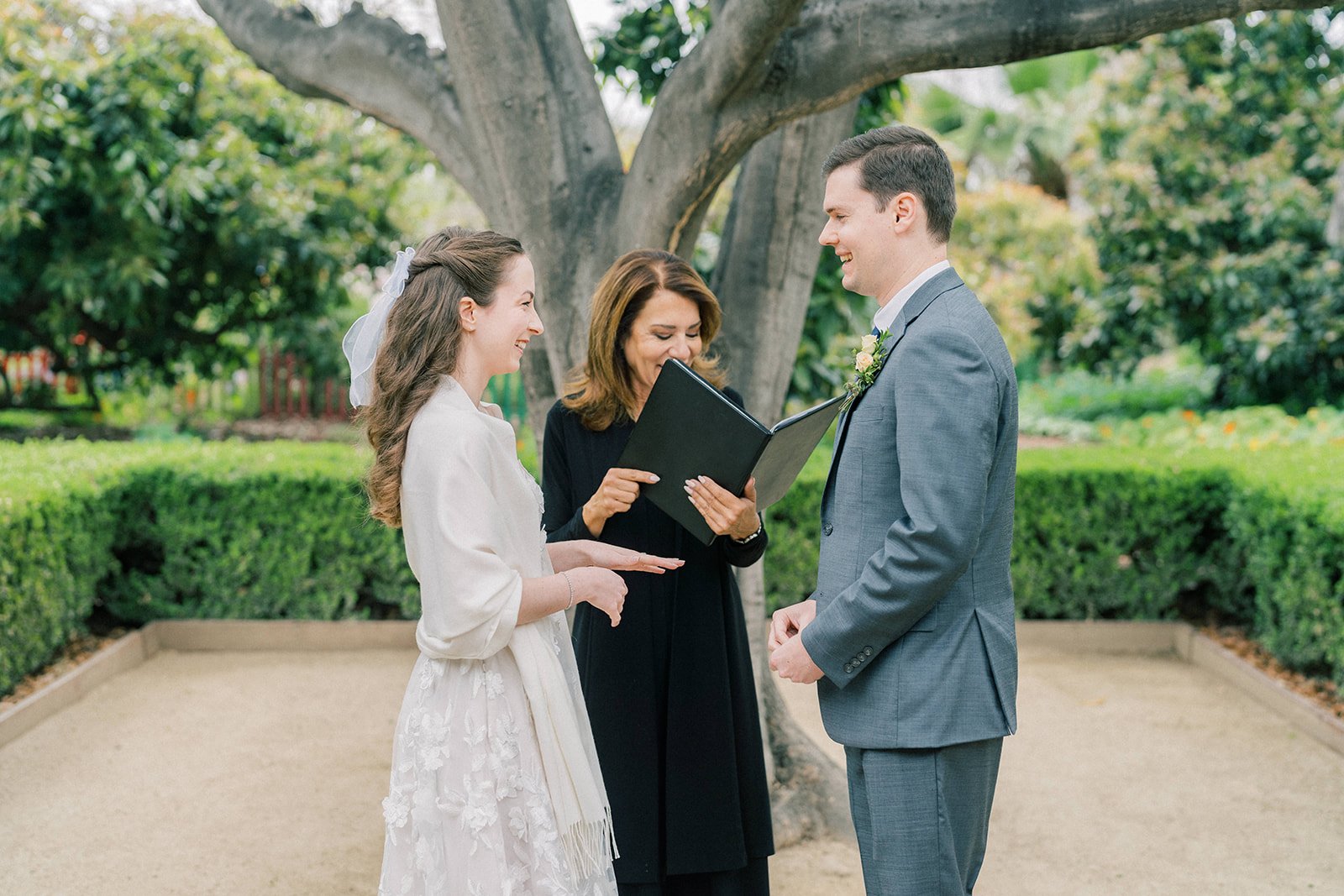 Bride extending her hand to receive her ring during their intimate garden ceremony