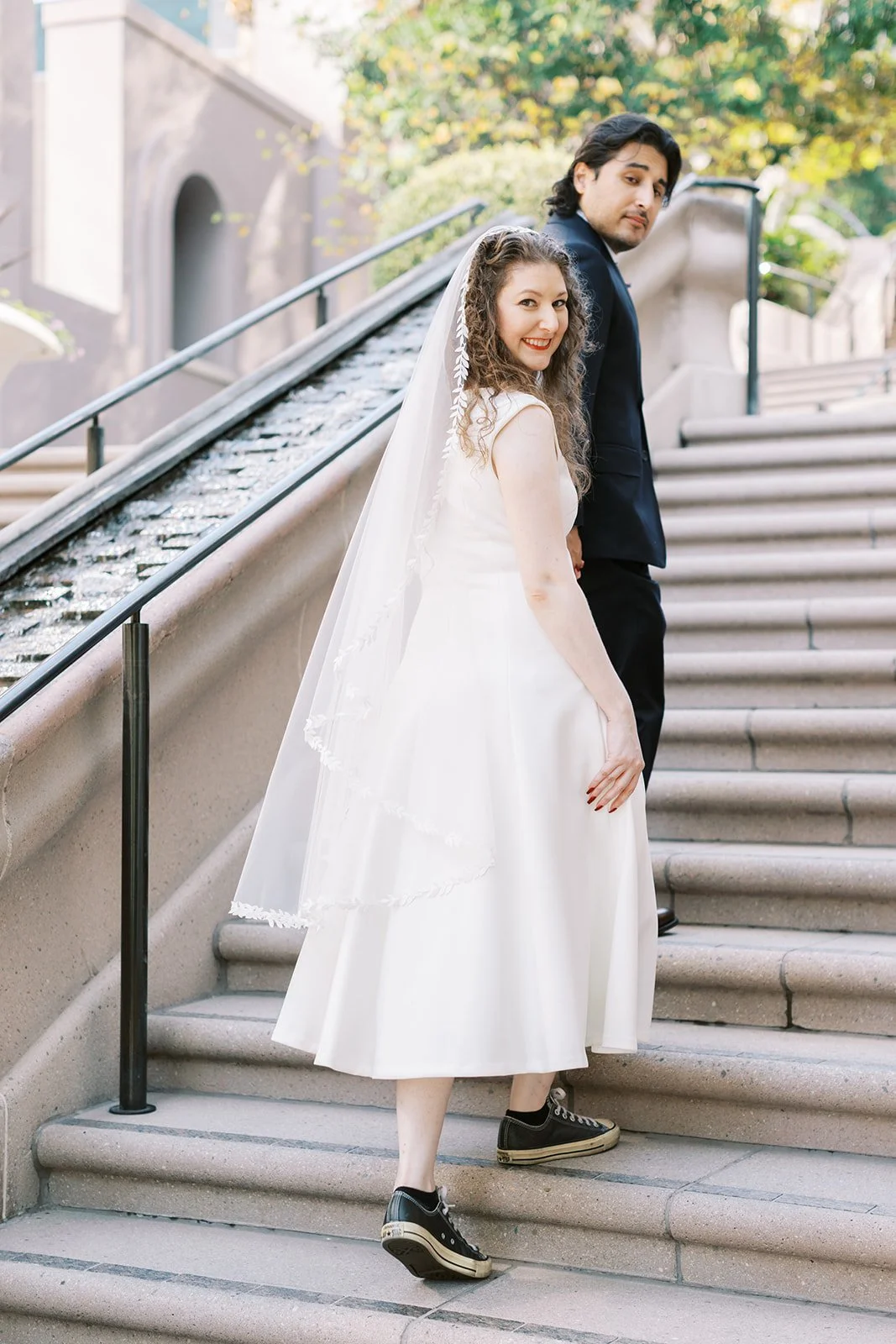 Bride and groom looking back as they walk up the steps outside the Los Angeles Central Library
