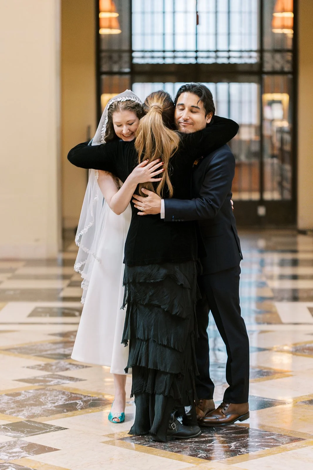 Officiant embracing the newlyweds after their ceremony in the Central Library rotunda