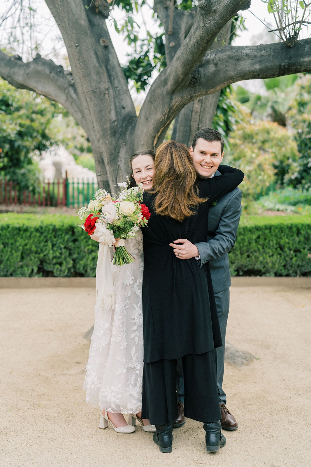 Newlyweds embracing their officiant after the ceremony