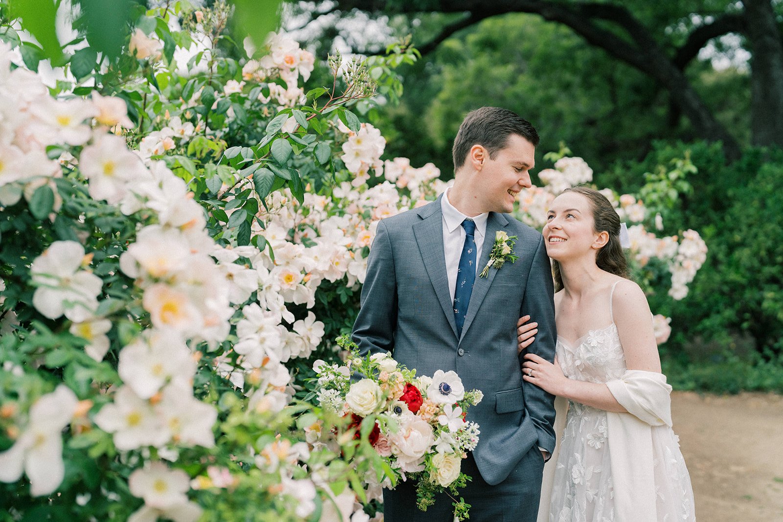 Bride gazing at the groom beside the rose bushes at the Fullerton Arboretum