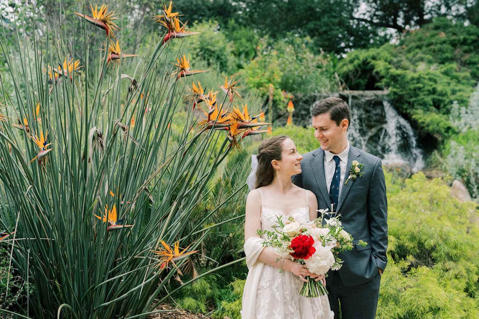 Bride and groom gazing at each other beside bird of paradise flowers in the gardens of the Fullerton Arboretum