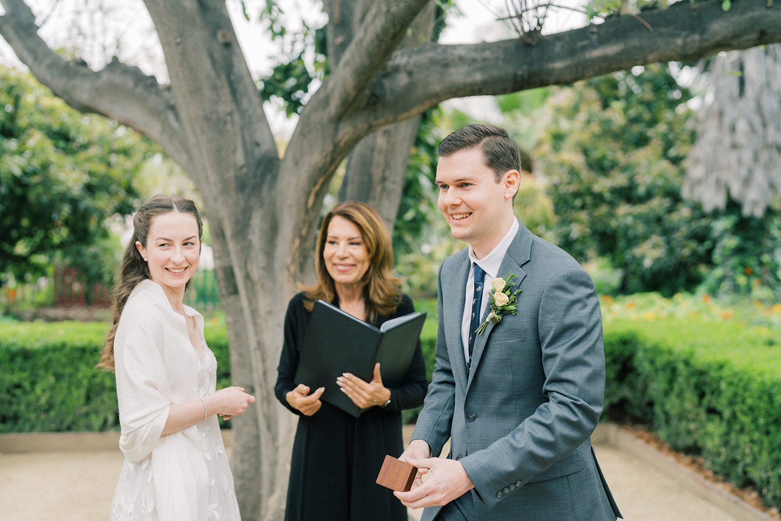 Officiant and couple smiling toward their guests during the ceremony