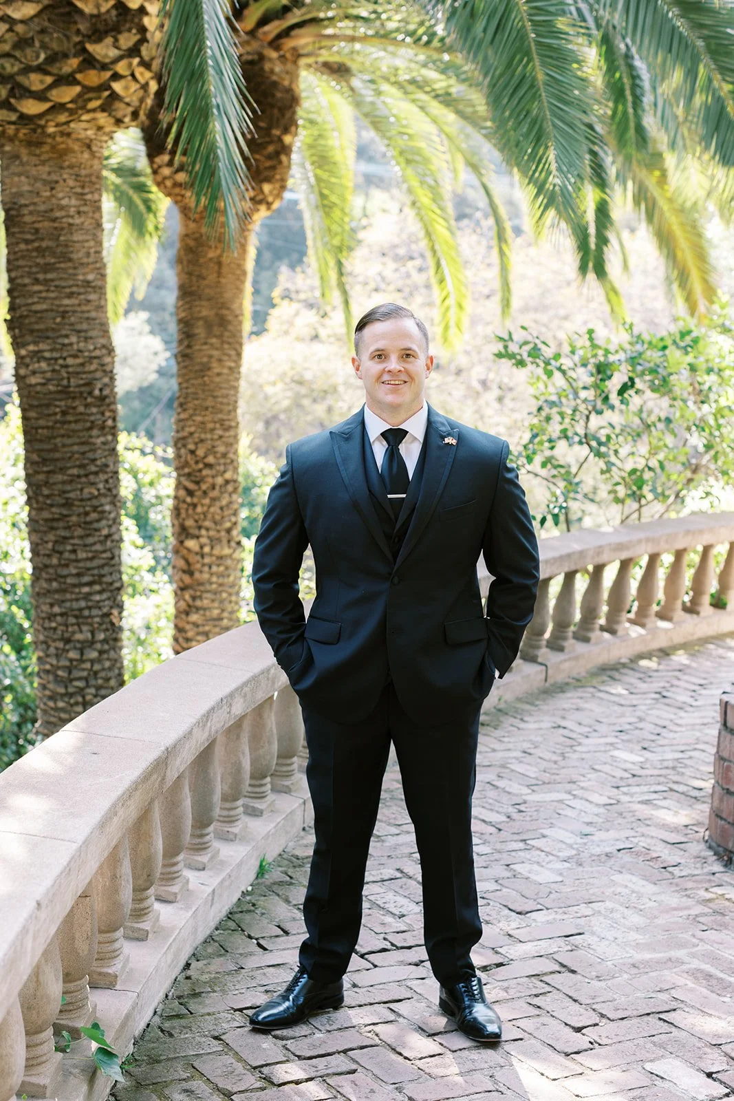 Portrait of the groom looking toward the camera on a walkway beside the house at the Houdini Estate