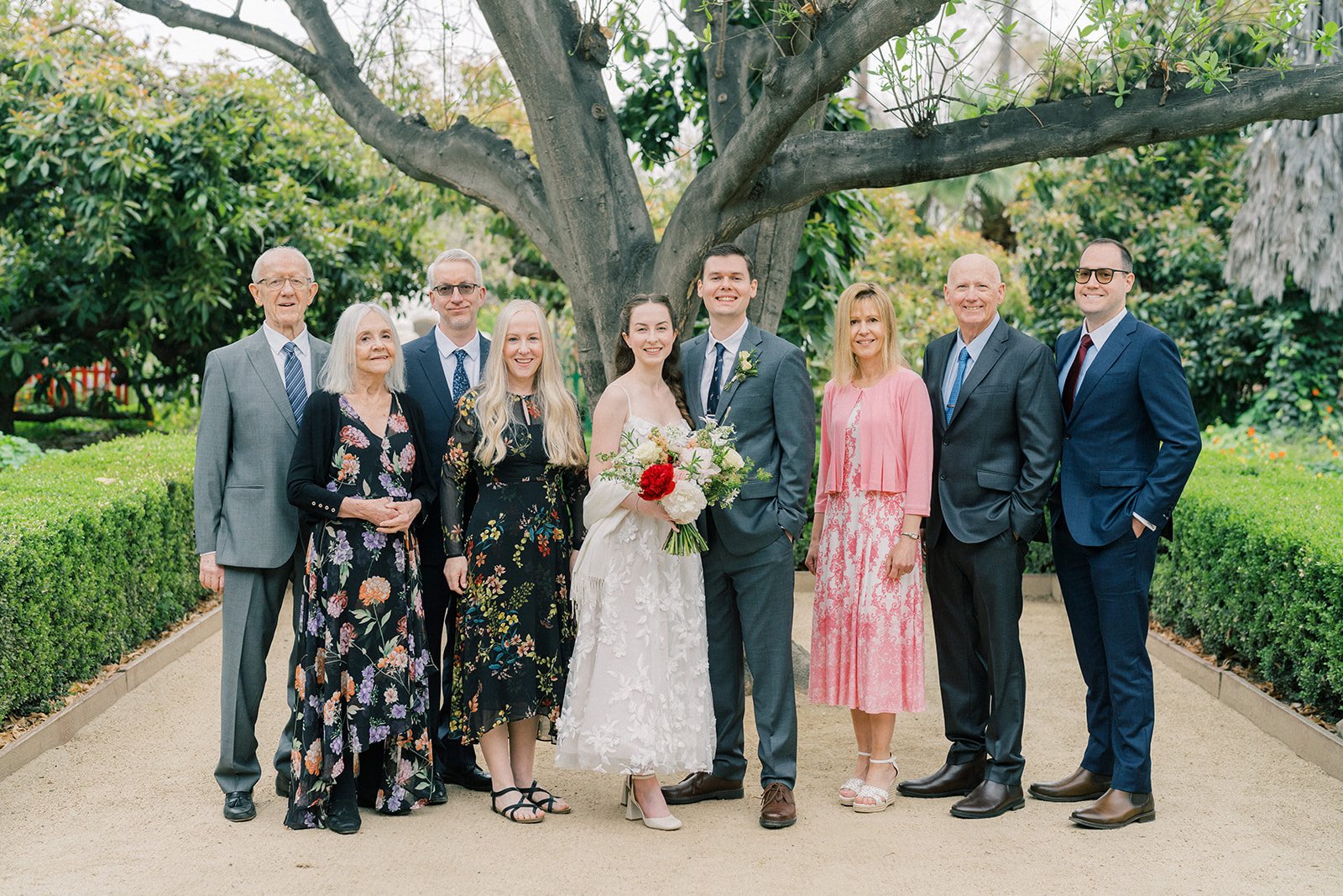 Portrait of the bride and groom with both of their families at their Fullerton Arboretum wedding