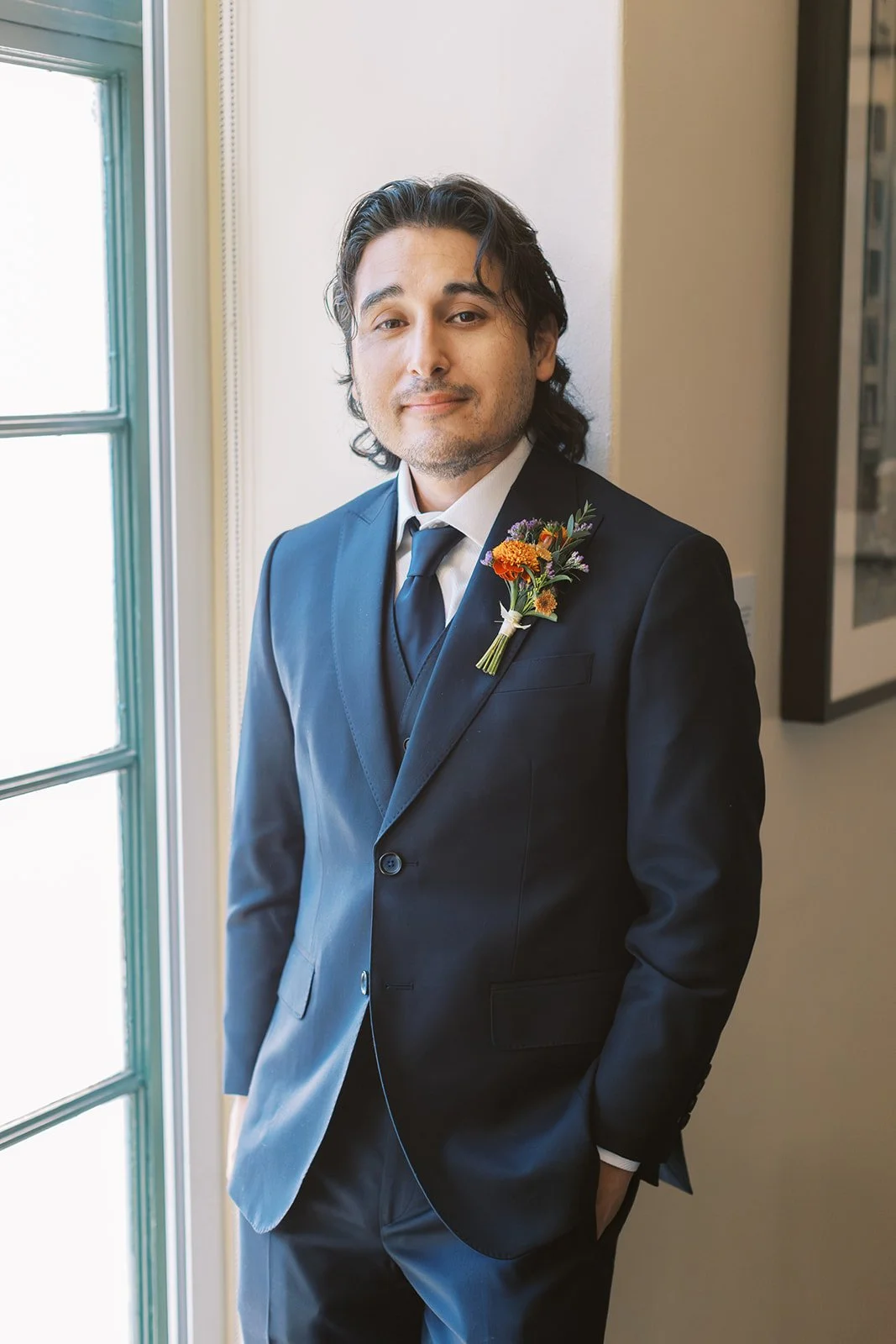 Portrait of the groom standing by a window on his wedding day