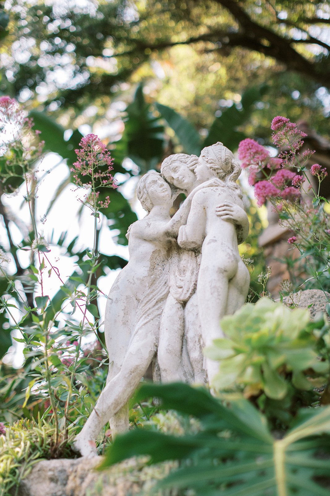 Stone statue of three women embracing in the gardens of the Houdini Estate