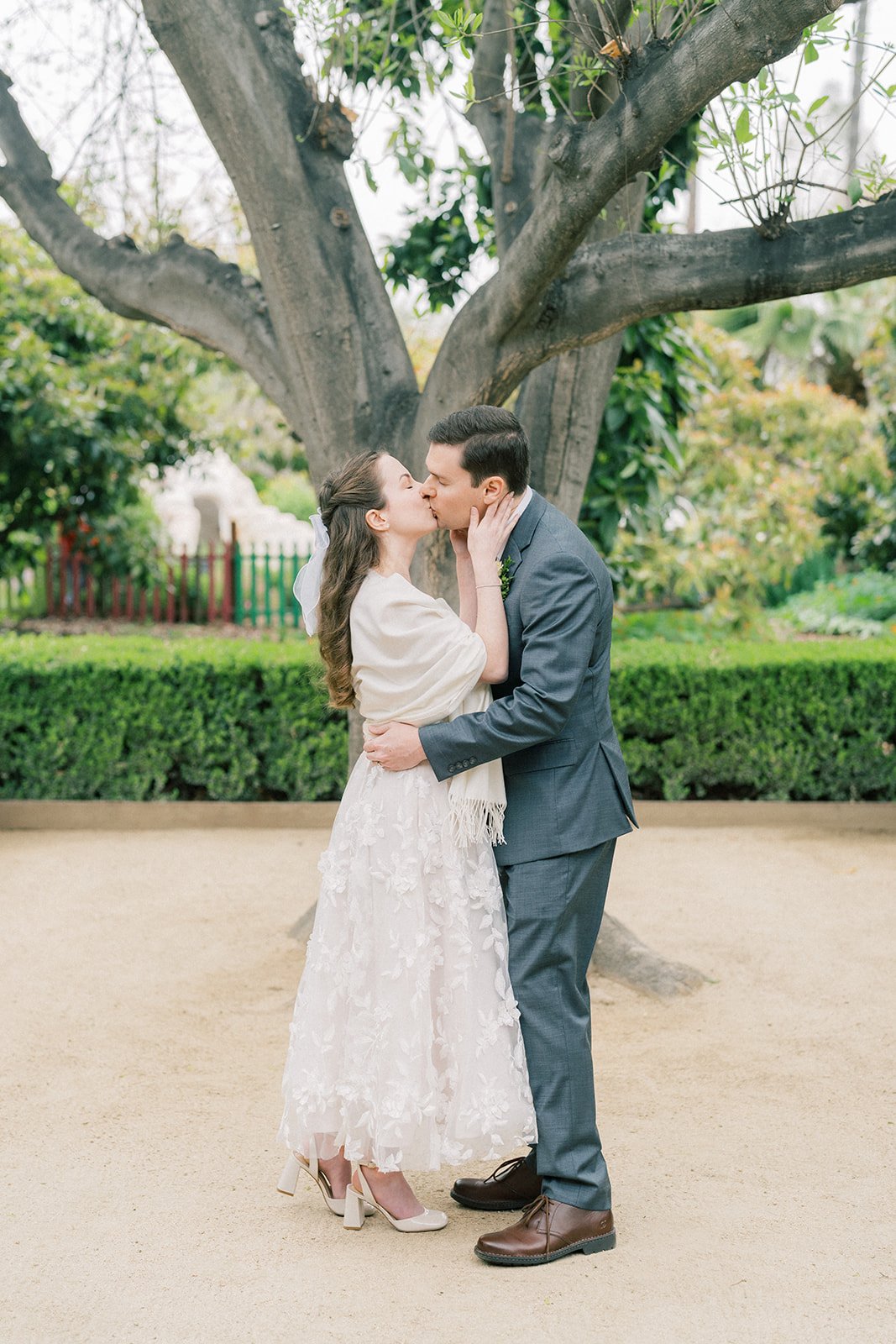 Bride and groom sharing their first kiss at the close of their elopement ceremony at the Fullerton Arboretum