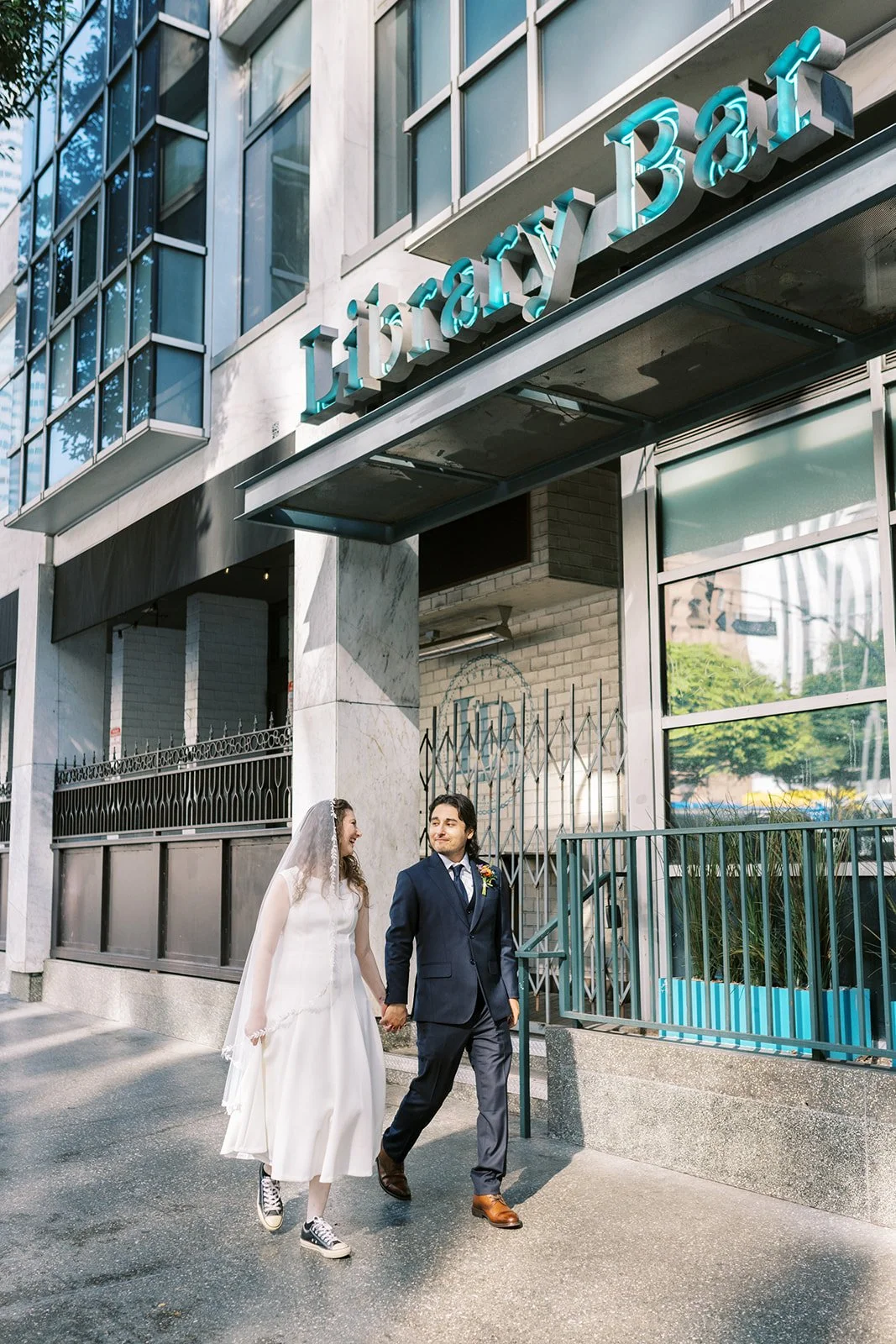 Bride and groom strolling through downtown Los Angeles past the Library Bar