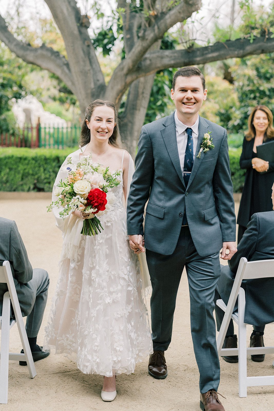 Joyful newlyweds walking back up the aisle after their garden wedding ceremony
