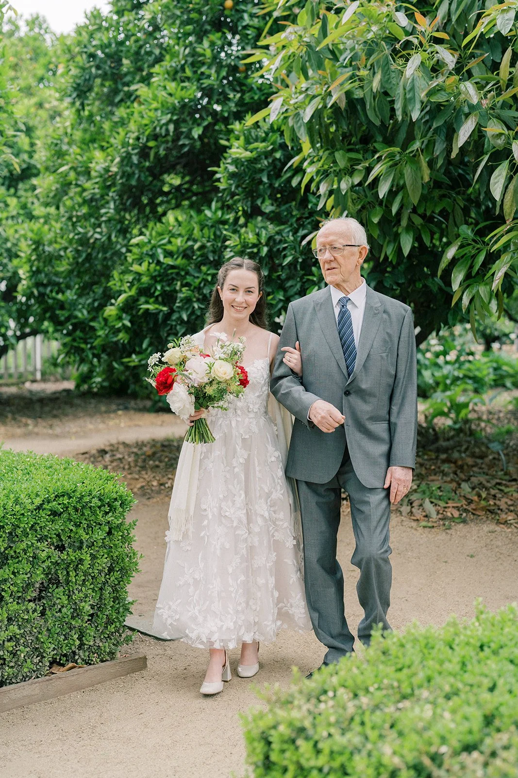 Bride walking down the aisle on her grandfather’s arm at her garden wedding