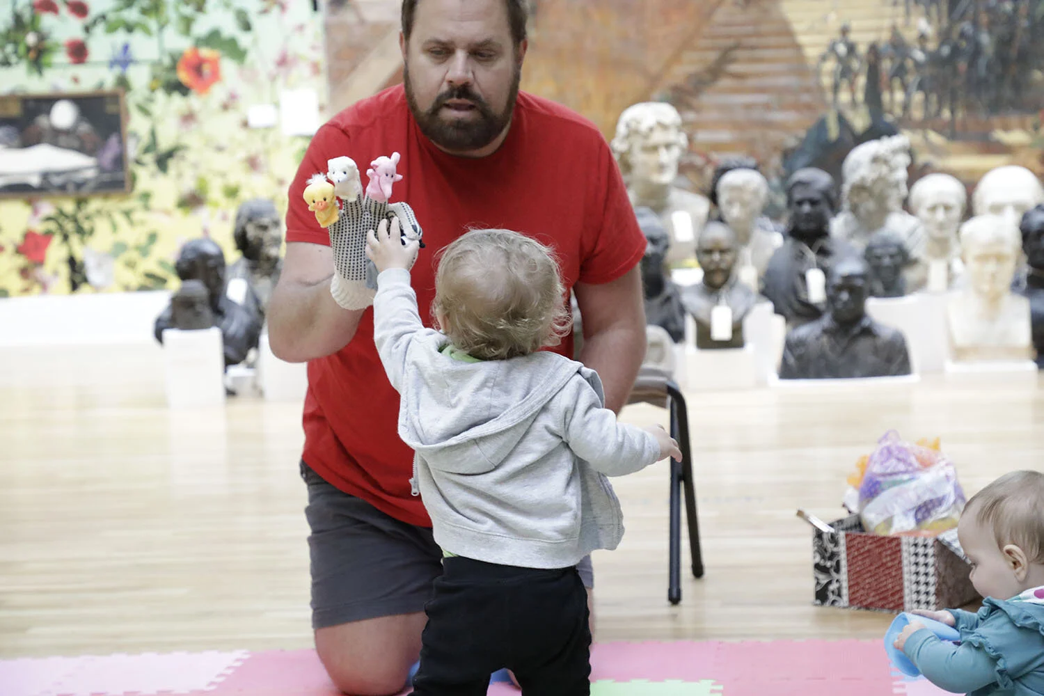 Family arts workshops: a toddler reaches out to teaching artists and animal finger puppets during Baby Artsplay!