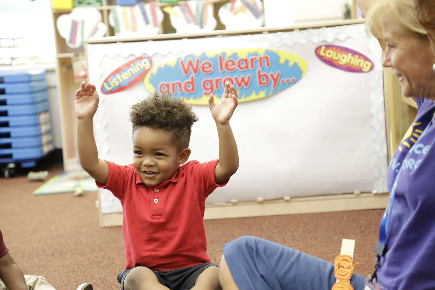  Louisiana Wolf Trap: toddler boy raises both arms in the air and smiles during an arts-integrated residency for early learners.  