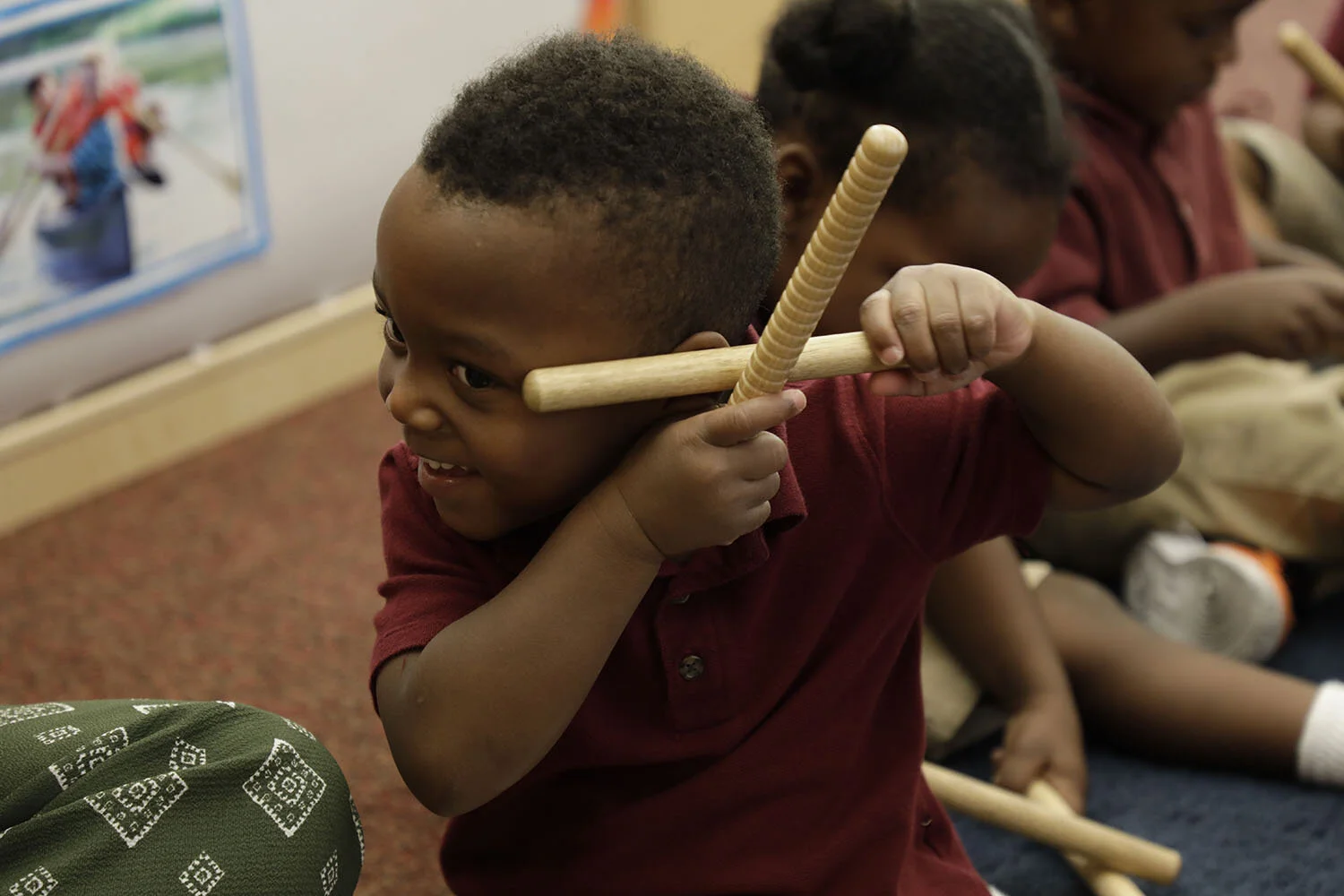  Louisiana Wolf Trap: during an arts-integrated residency, a toddler boy smiles as he listens closely to the clave sticks he is playing. 