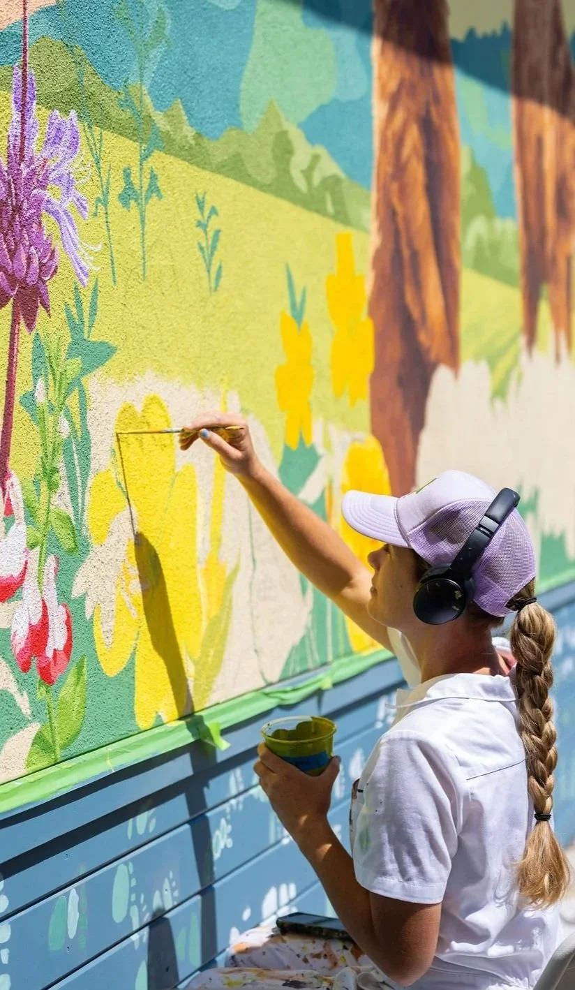 Brittany Costanzo of Costanzo Creative hand painting a mural at Bradley Elementary School in Santa Cruz, CA