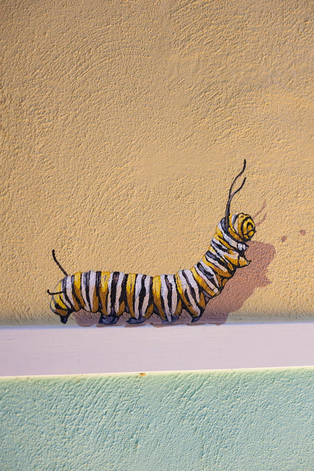 Santa Cruz Toddler Care Center Mural close up of yellow, black, and white striped a caterpillar by Brittany Costanzo Creative 2026