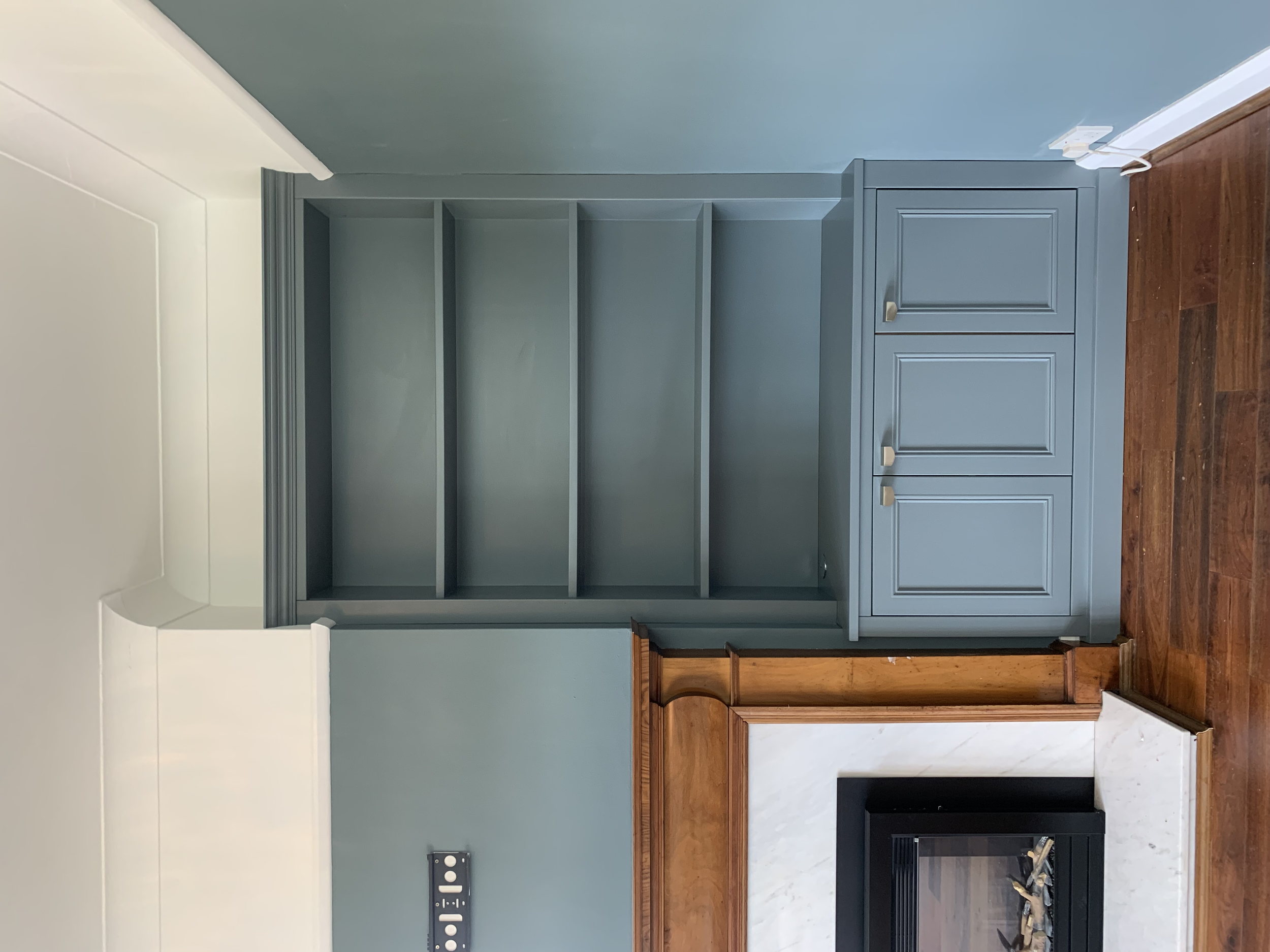 Empty blue bookshelf next to fireplace with wooden trim on wall in living room.