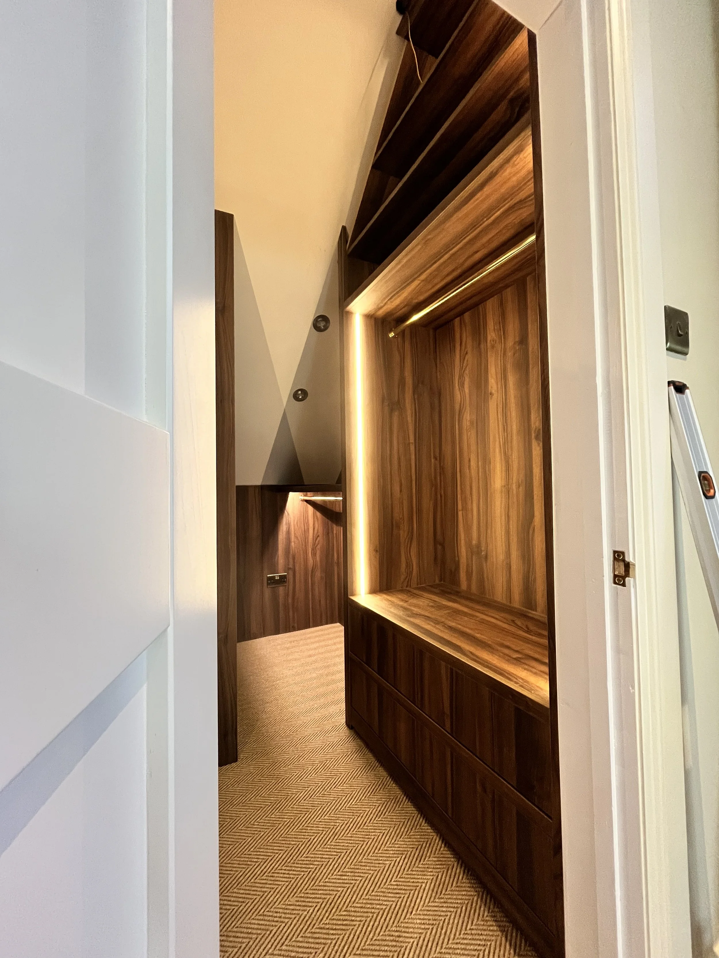 Modern wooden closet interior with open shelves, drawers, and concealed lighting.