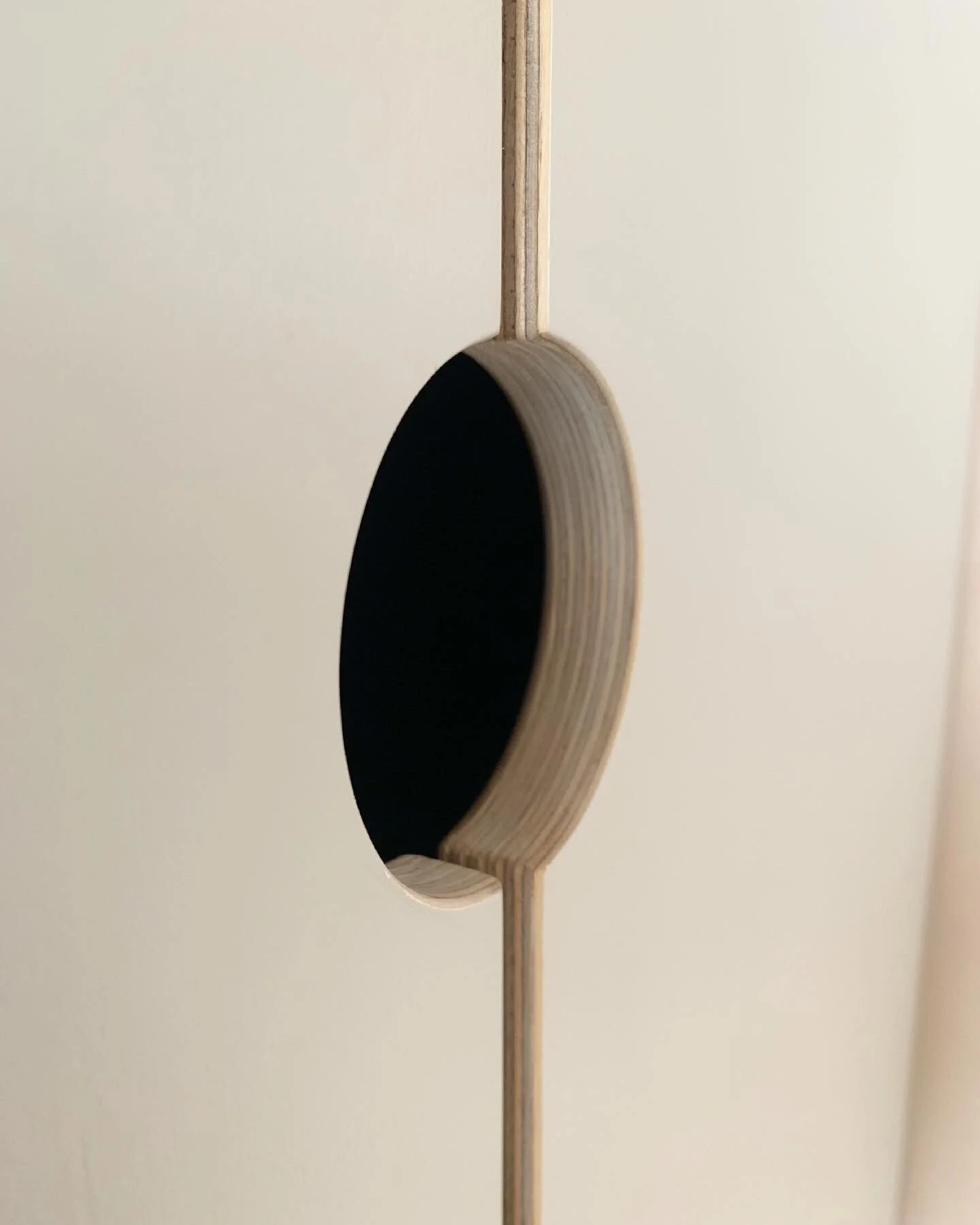 Close-up of a circular hole in a beige, smooth panel with a wooden frame around the hole.