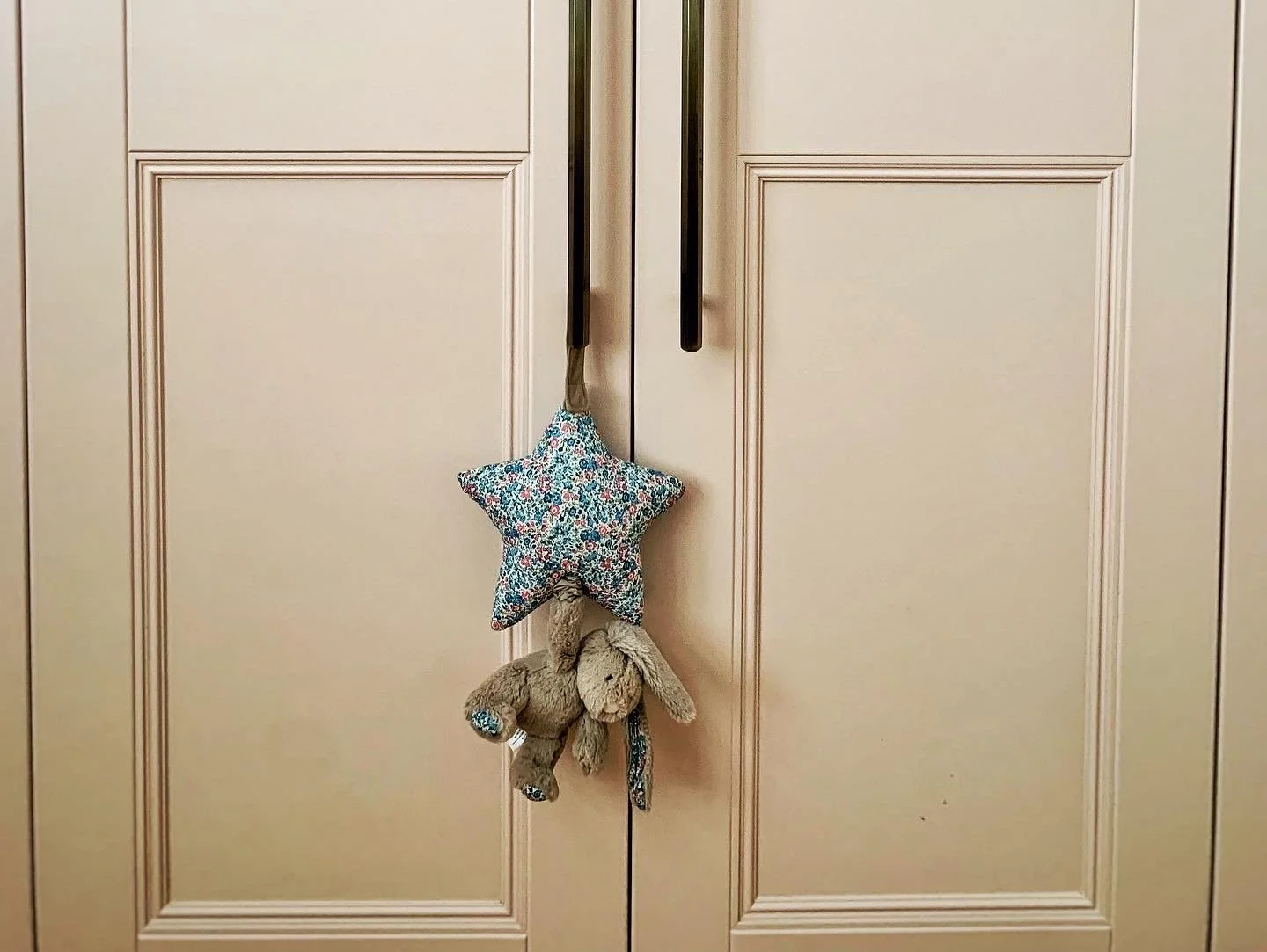 Closet doors with a star-shaped plush toy and stuffed bunny hanging from the door handle.