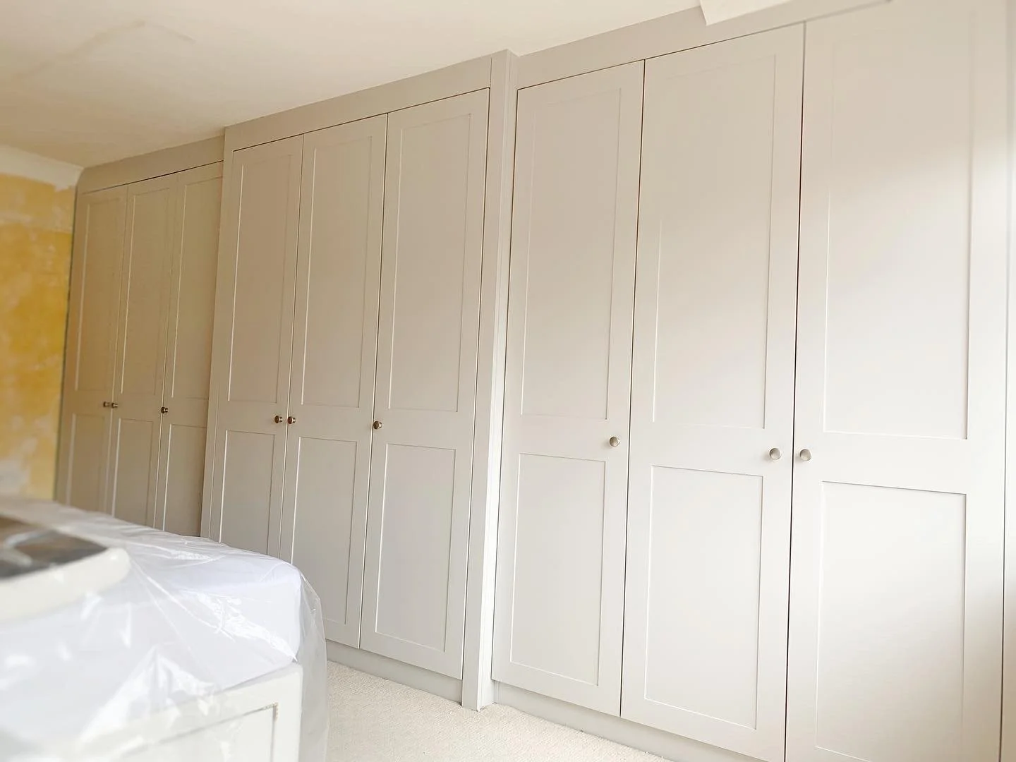 White built-in closet with multiple doors in a bedroom.