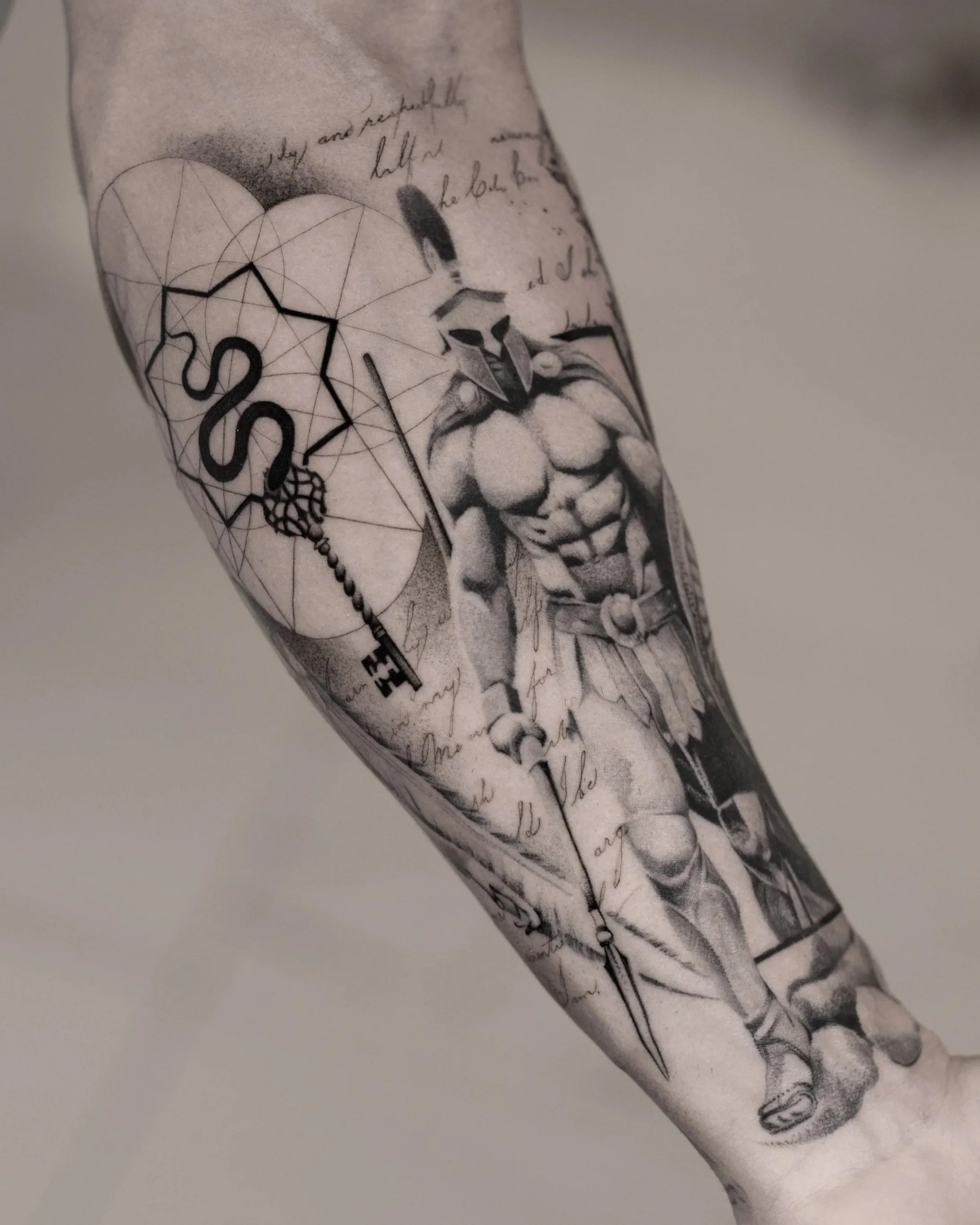 Black and grey forearm tattoo combining a realistic helmeted warrior with fine geometric linework, a decorative key and handwritten script.