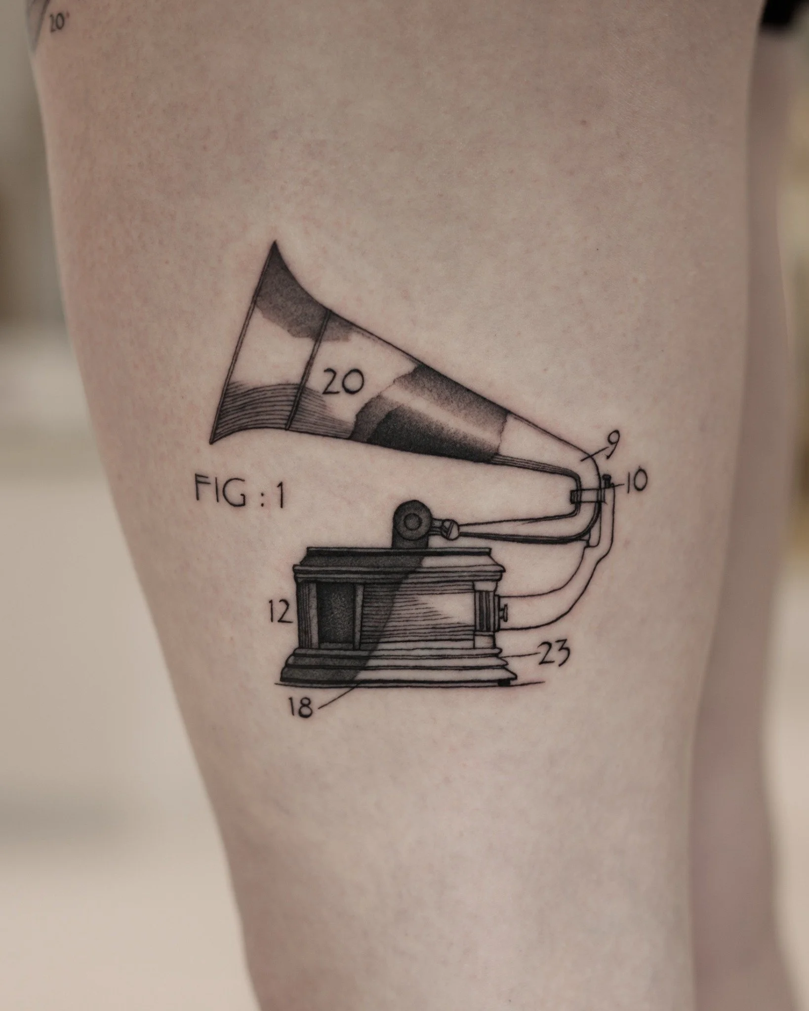 Black and grey tattoo of a vintage gramophone with a large horn, shaded base and numbered technical-diagram labels.
