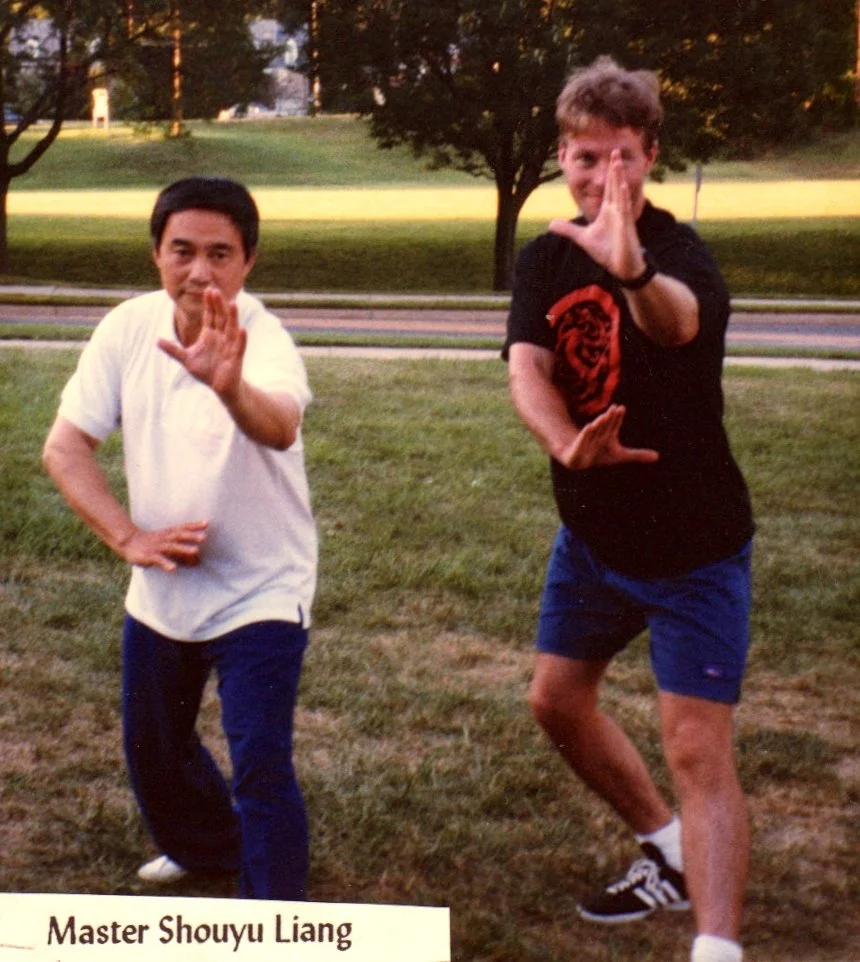 Master Shouyu Liang (36 Xiaoyaoshuai also known as San Shou Kuai Jiao) &  Sifu Kelly performing martial arts poses outdoors on grass.