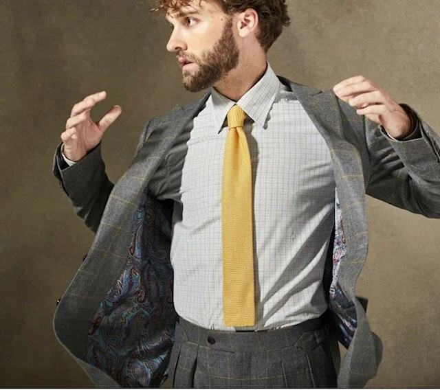 Grey windowpane suit with checkered dress shirt and yellow tie.