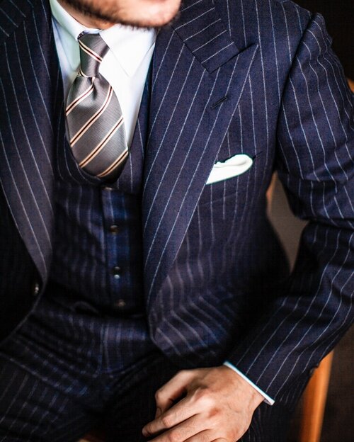 Navy pinstripe three piece custom suit with white shirt and silver tie