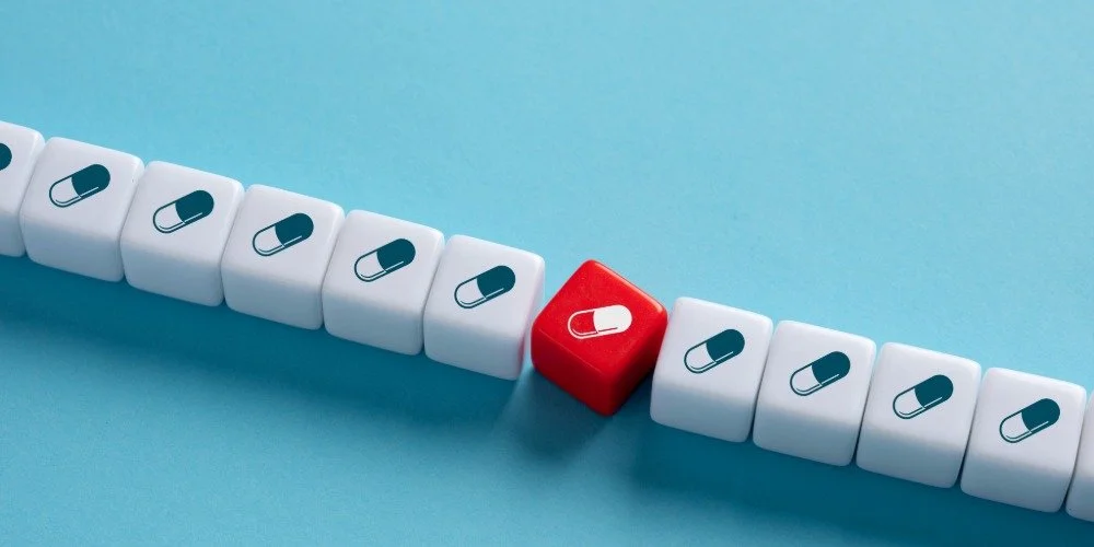 line of white blocks with medication symbol, with a singular one in red and tilted