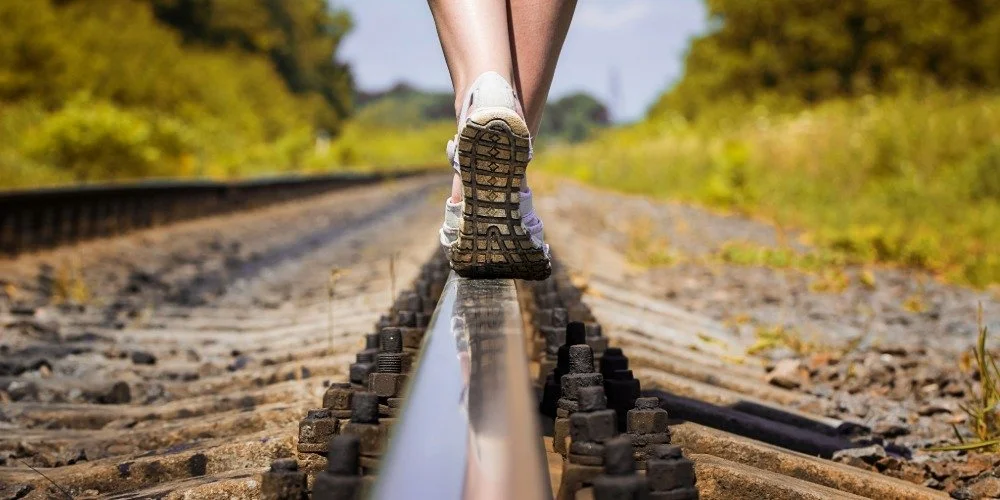 person walking on train track rail