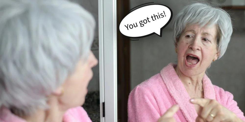 woman looking at herself in the mirror and telling herself, "you got this!"