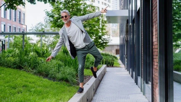 man balancing on curb with large smile on his face