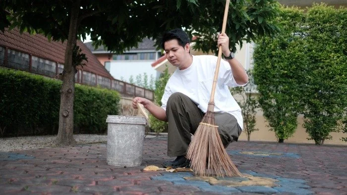 man sweeping ground while crouching