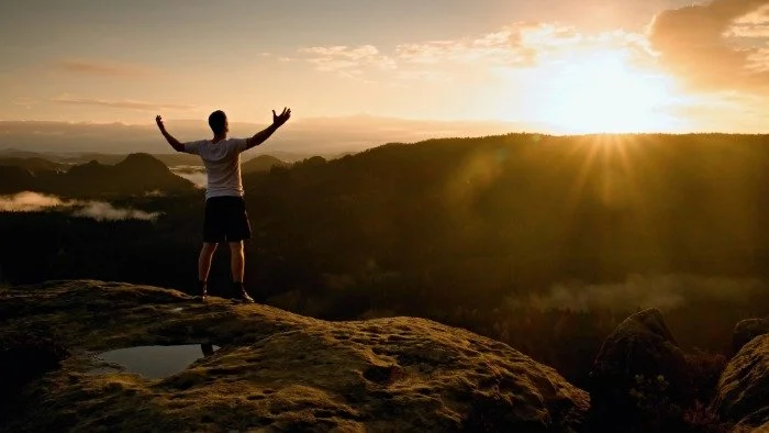 man triumphant looking out over scenery